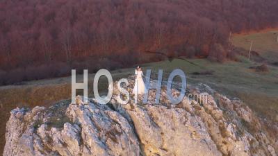 Bride In White Wedding Dress Standing On A Cliff - Video Drone Footage