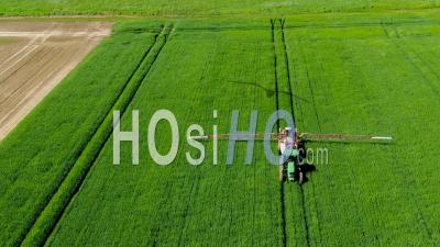 Tractor Spraying Chemical Products On Wheat Field - Video Drone Footage