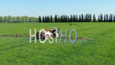 Tractor Spraying Chemical Products On Wheat Field - Video Drone Footage