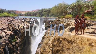 Vue Aérienne De Deux Femmes De La Tribu Himba Devant Des Cascades D'epupa à La Frontière Entre L'angola Et La Namibie, En Afriqu - Vidéo Drone
