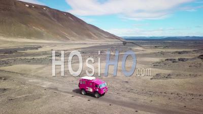 Aerial View Of A Rare Pink Land Rover 101 Driving Through The Outback Highlands Of Desolate Iceland - Video Drone Footage