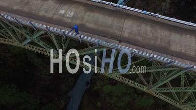 Aerial View Of A Man Standing On A Steel Suspension Bridge Over The Skokomish River In Washington, Usa - Video Drone Footage