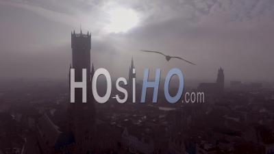 Aerial View Of A Mysterious Foggy Day Of Bruges, Belgium With Cathedral Churches And Spires In Distance - Video Drone Footage