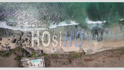 Top View Of Waves Breaking On The Beach Next To A Cliff - Aerial Video By Drone 