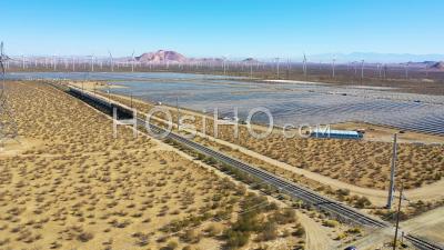 A Freight Train Traveling Through Vast Solar And Wind Array In Mojave Desert California - Aerial Video By Drone