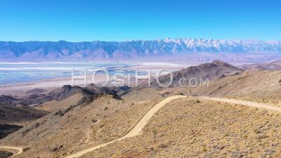 A 4wd Wheel Drive Vehicle On A Dirt Road Through The Eastern Sierras With Mt. Whitney And The Owens Valley Desert And Dry Lake Bed Distant - Aerial Video By Drone