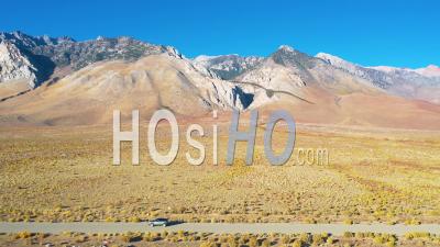 Aerial Video Of A 4wd Wheel Drive Vehicle On A Road In Front Of The Eastern Sierras With Mt. Whitney In Ther Distance Suggesting Remote Road Trip Adventure - Video Drone Footage