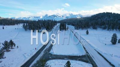 2020 - Vue Aérienne De Voitures Roulant Lentement Sur La Route De Montagne Couverte De Neige Glacée Dans Les Montagnes De L'est De La Sierra Nevada Près De Mammoth En Californie - Vidéo Par Drone