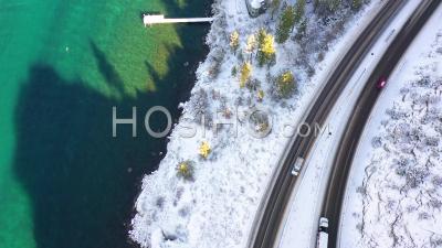 2020 - Top Down Aerial Pov Of A Car Traveling On A Snowy Road Through A Tunnel Beside A Lake. - Video Drone Footage