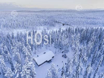 Aerial Photo Of A Cabin In A Snow Covered Winter Forest Of Trees At Sunset In The Arctic Circle In Finnish Lapland, Finland - Aerial Photography