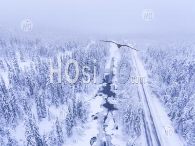 Vue Aérienne De La Route D'hiver Par Rivière Gelée Et Paysage Forestier Couvert De Neige Montrant Des Paysages De Laponie En Scandinavie En Finlande - Photographie Aérienne