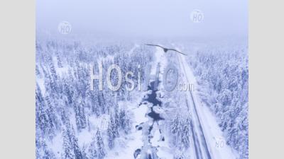 Aerial Of Winter Road By Frozen River And Snow Covered Forest Landscape Showing Lapland Scenery In Scandinavia In Finland - Aerial Photography