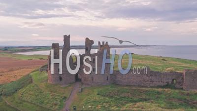 Dunstanburgh Castle At Sunset In Northumberland, England, Uk. Aerial Drone View
