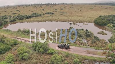 4 Wheel Drive Vehicle Driving Through Muddy Puddle In Aberdare National Park, Kenya, Africa. Aerial Drone View