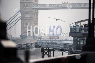 Red London Bus Driving Over Tower Bridge And River Thames In Foggy Misty Weather In London City Centre On Coronavirus Covid-19 Lockdown Day One, England, Uk