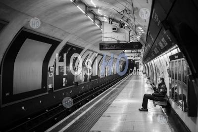 Quiet, Empty London Underground Tube Station In Coronavirus Covid-19 Pandemic Lockdown, With One Lone Person On Public Transport Train Platform During Travel Ban