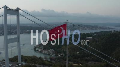 Turkish Flag Waving In Wind In Front Of Istanbul Bosphorus Bridge, Aerial Medium Shot Slide Right - Video Drone Footage