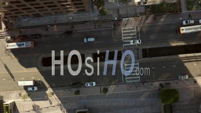 Young Man Laying On Street Slow Birds Eye View Flight Over Downtown Los Angeles California Grand Avenue In Beautiful Sunrise Light With View Of Skyscraper Rooftops And Car Traffic Passing 4k - Video Drone Footage