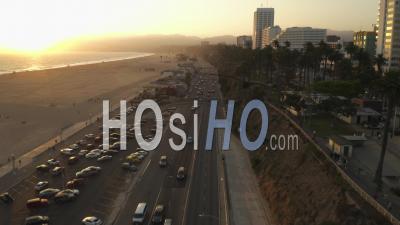 Vue De L'autoroute De La Côte Pacifique à Côté De La Jetée De Santa Monica, Los Angeles Avec Trafic Léger Et Vue Sur L'océan Par Au Coucher Du Soleil, été 4k - Drone Vidéo
