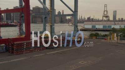 Low Flying Aerial Shot Through The Container Terminal Crane Into Reveal Of The New York City Skyline And A Boat Arriving Into The Harbor 4k - Video Drone Footage