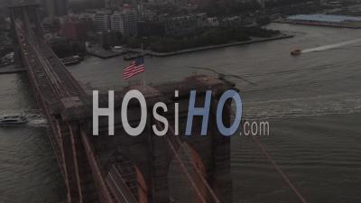 Close Up Circle Flight Over Brooklyn Bridge With American Flag And East River View Manhattan New York City Skyline In Beautiful 4k - Video Drone Footage