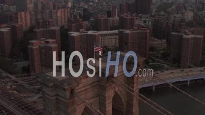 Close Up Circle Flight Over Brooklyn Bridge With American Flag And Foggy Manhattan New York City Skyline In Beautiful 4k - Video Drone Footage