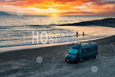 Aerial Photo Of Campervan On Abandoned Beach Against Beutiful Sunset. People Bathing In The Sparkling Sea. - Aerial Photography