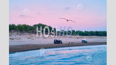 Off Road Campervans And Travellers Standing On Sandy Beach Against Red Evening Sky - Aerial Photography