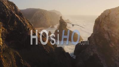 Aerial Drone View Of Dramatic Coastal Landscape And Scenery Of Cliffs, Rock Formations And Rocks On The Atlantic Coast Of Portugal, Europe With Orange Sunset Light