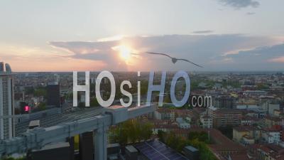 Aerial Panoramic View Of City Against Setting Sun. Backwards Reveal Of Tall Modern Apartment Houses With Green Plants On Facade. Milano, Italy. - Video Drone Footage