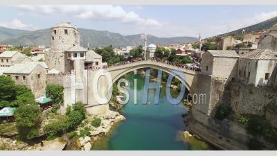 A Man Dives From The Crowded Mostar Bridge Into The Neretva River Below In Mostar, Bosnia - Video Drone Footage