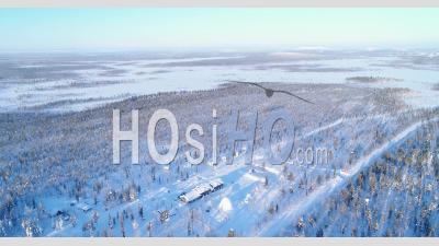 An Aerial View Shows Trees And Lodgings Of The Snow-Covered Northern Lights Ranch In Kongas, Finland - Video Drone Footage