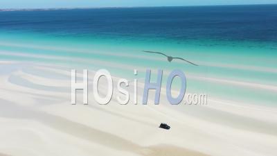 2020 - Excellent Aerial Shot Of A Van Driving Along The Shoreline White Sands Of Flaherty Beach Near Clear Blue Waters - Video Drone Footage