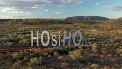 2021 - Excellent Aerial Shot Of A Coal Train Traveling Past Shrubs And Mountains In Tom Price, Australia - Video Drone Footage