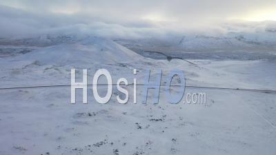 Vue Aérienne De Voitures Conduisant Le Long D'une Route Couverte De Neige Par Des Montagnes En Islande - Vidéo Par Drone